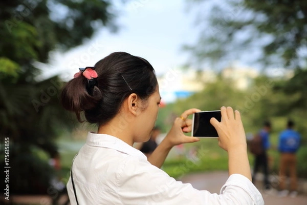 Obraz スマートフォンで写真を撮る女性