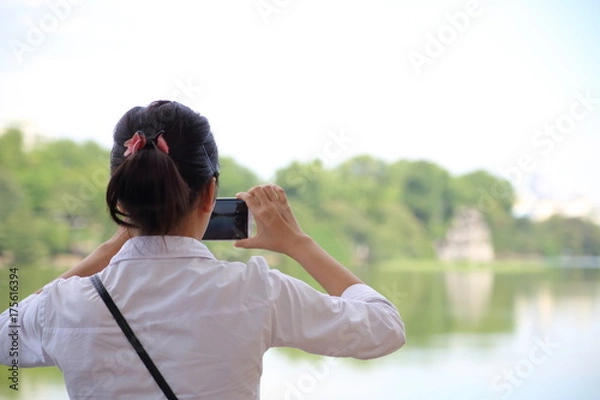 Obraz スマートフォンで写真を撮る女性