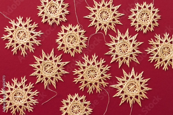 Obraz Snowflakes are made of straw on a red background. Christmas decor. Top view. Straw weaving. Lutsk, Ukraine
