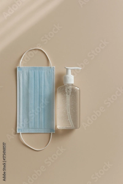 Obraz AI-generated clean flat lay of medical face mask and sanitizer bottle on beige background — minimalist hygiene concept