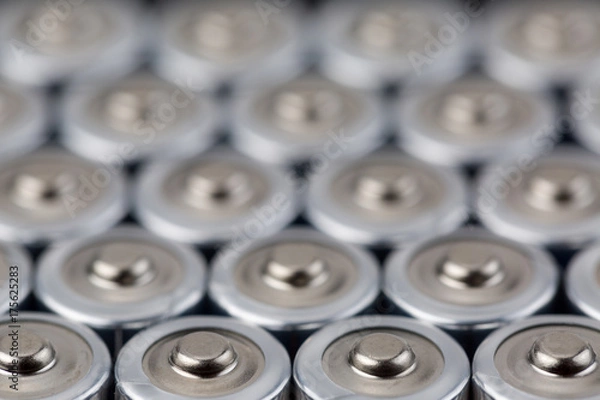 Fototapeta Close up top view on blurred rows of AA batteries energy abstract background of batteries. Shallow depth of field.