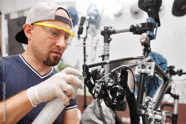 Fototapeta Mechanic repairing bicycle in his workshop