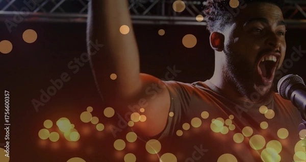 Fototapeta Adult singer raising arm, singing on stage under truss with microphone and bokeh lights, copy space