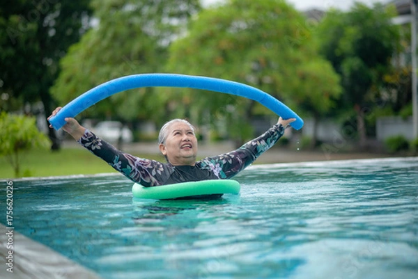 Fototapeta Elderly woman enjoying relaxing moment swimming pool, smiling happily while resting on inflatable float concepts related to wellness, summer relaxation, family life, and senior health care.