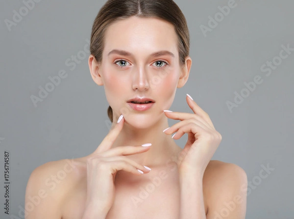 Obraz A beautiful young woman with a perfect face touches her facial skin with her fingertips.