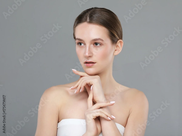 Obraz A beautiful young woman with a perfect face touches her facial skin with her fingertips.