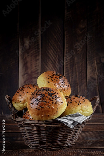 Fototapeta Homemade freshly baked plain golden brown soft hamburger buns topped with sesame seeds against wooden background. Homebaking, freshness, bbq concept