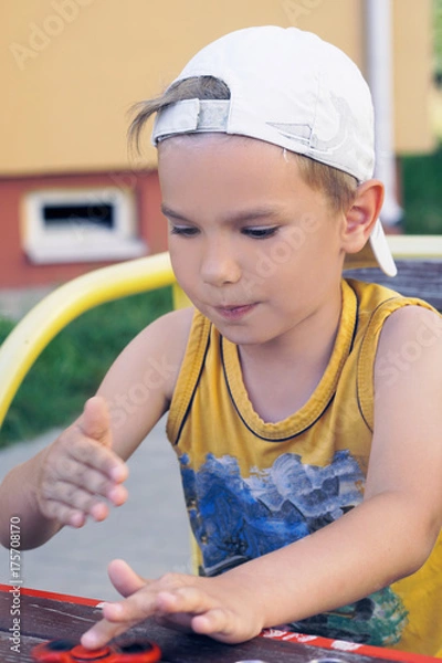 Obraz Young schoolboy holding popular fidget spinner toy - close up portrait. Happy smiling child playing with Spinner.