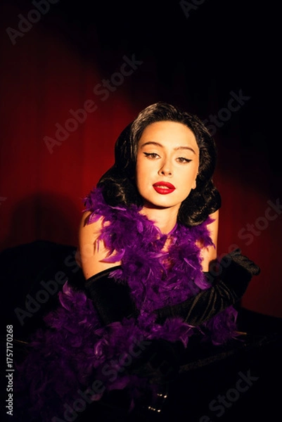 Fototapeta Performing artist in a purple feather boa poses on a grand piano with red curtains in the background during a glamorous evening event