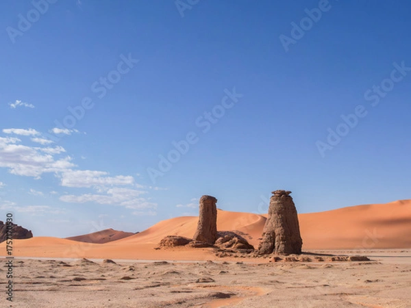 Obraz Desert landscape of the Red Tadrart with rock formations and golden sand under a blue sky. Natural scenery of the Algerian Sahara.