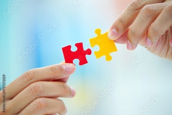 Fototapeta Hands Connecting Red and Yellow Puzzle Pieces, Symbolizing Collaboration and Problem Solving