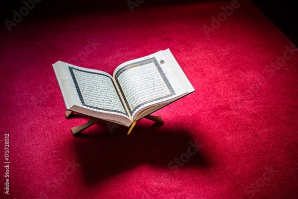 Fototapeta Holy book of Koran on stand on red carpet with vignetting affect.