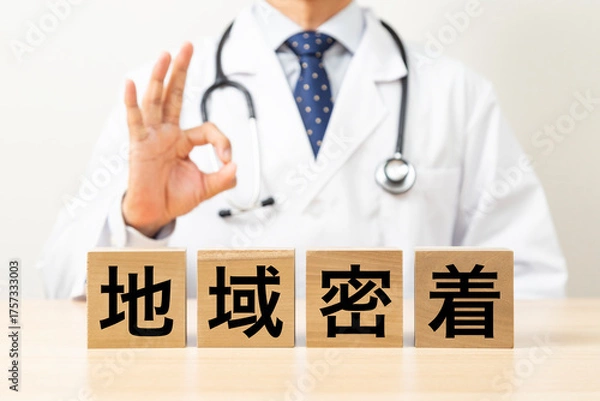 Fototapeta 「地域密着」と書かれたブロックとOKサインをする医師