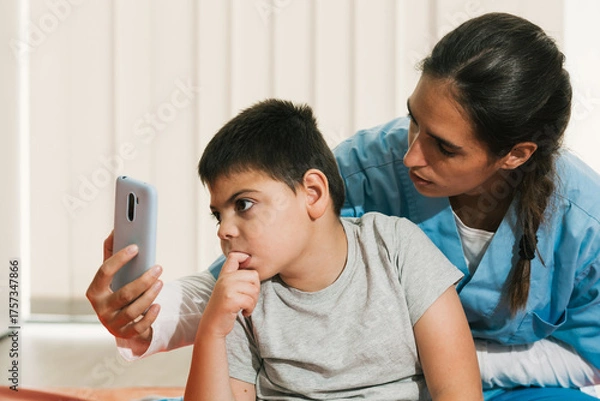 Fototapeta Physiotherapist assisting child with cerebral palsy using smartphone for visual tracking and attention therapy