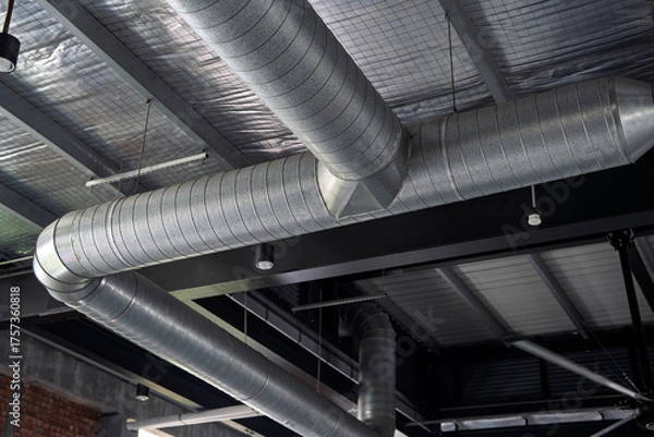 Obraz Close-up view of a metallic air duct ventilation system installed along the ceiling of a modern industrial-style building.