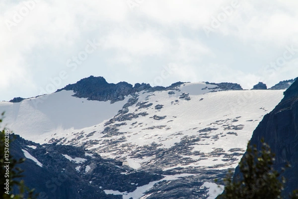 Fototapeta Close-up of a snow-covered mountain ridge under a cloudy sky, natural landscape