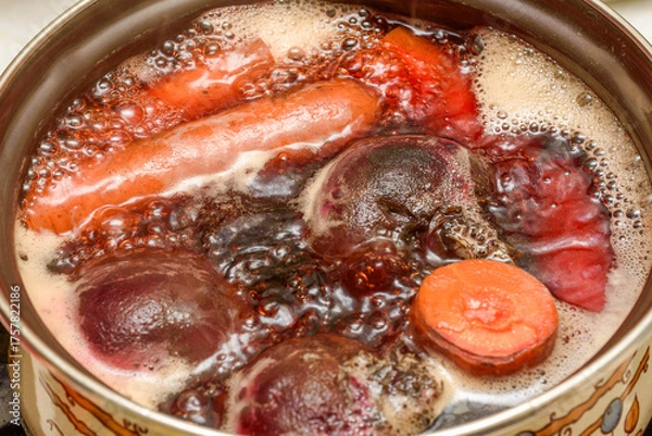 Obraz Carrots and beets are cooked in a saucepan in boiling water.