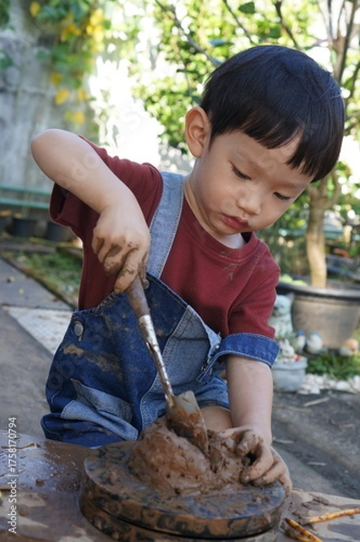 Obraz Little child's hands kneading and molding a lump of clay on a spinning wheel, creating a ceramic product