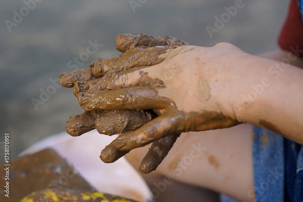 Obraz Little child's hands kneading and molding a lump of clay on a spinning wheel, creating earth ware
