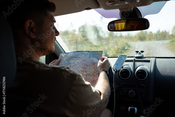 Fototapeta A man in a car is studying a road map