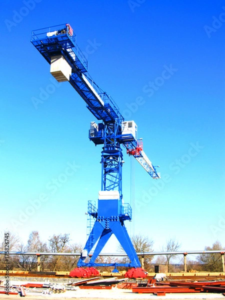 Fototapeta The crane stands on the rails against the blue sky.