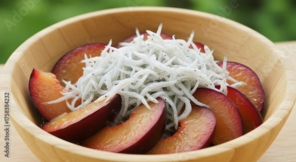 Obraz Close up of plum slices and small fish on wooden bowl