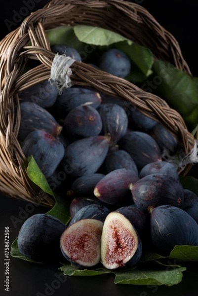 Fototapeta Fichi maturi in un cesto di vimini su sfondo nero