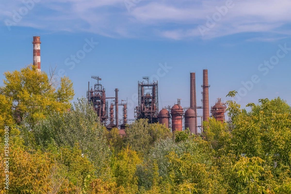 Fototapeta Abandoned industrial complex surrounded by vibrant greenery