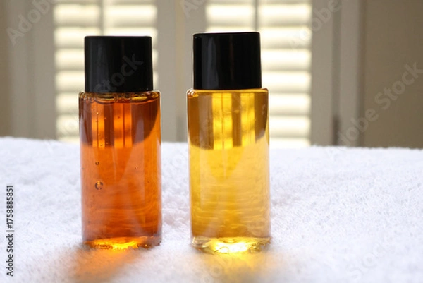 Fototapeta Travel size toiletries bottles for hotel amenities showing shampoo and conditioner on white towel