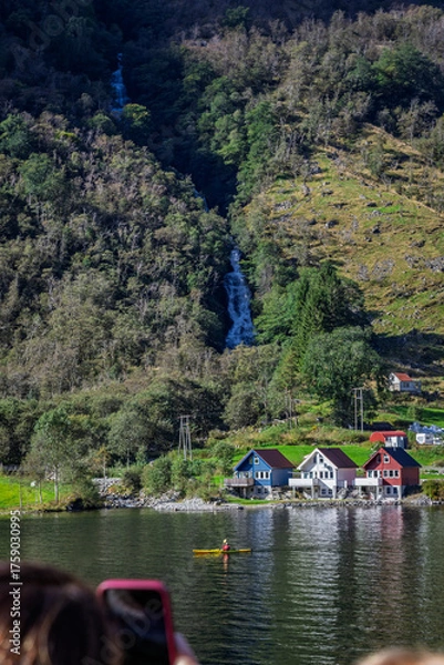 Fototapeta People admiring a lonely canoe at the bottom of a waterfall in Bakka, Norway