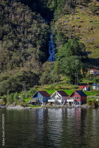 Fototapeta Houses at the bottom of a waterfall in Bakka, Norway