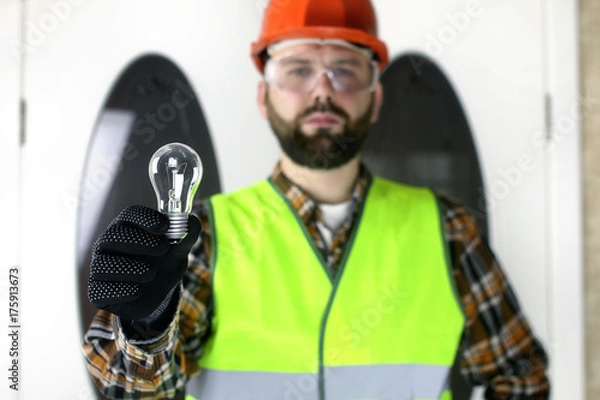 Obraz The man in a helmet holding a light bulb