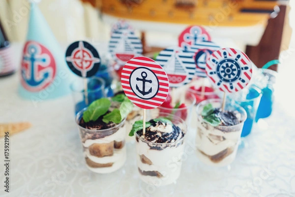 Fototapeta Glasses with tiramissu and colorful berries decorated with anchors, yachts and other marine theme