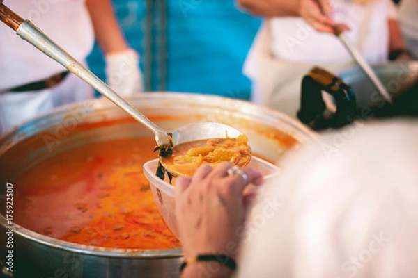 Fototapeta Receiving food for the poor from volunteers, concept of feeding, Homeless people receive delicious charity food from volunteers: concept of helping by donating food