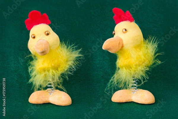Fototapeta Two cheerful yellow spring chickens with fluffy feathers and red combs stand playfully on a vibrant green background, ideal for holiday and children's themes.