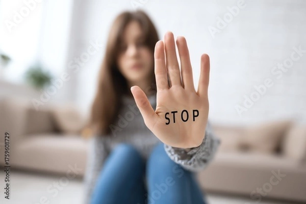 Fototapeta A young woman extends her hand with the word 'STOP' written on it, symbolizing the importance of setting boundaries and advocating for personal space in today's society.