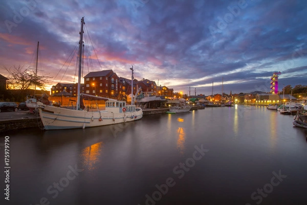 Fototapeta A white masted vessel is moored in a harbor in the city of Exeter. Other vessels are also visible. Colorful sunset. Exeter. Devon. England