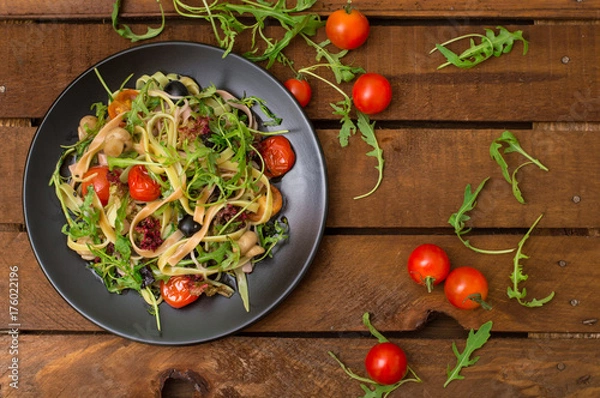 Fototapeta Italian bucatini with shrimp, arugula and cherry tomatoes. Wooden background. Close-up. Top view