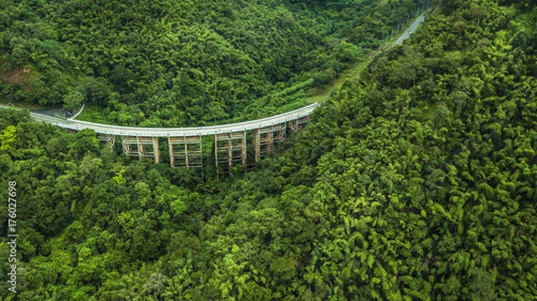 Fototapeta An aerial view of  Road or bridge is in the middle of a forest