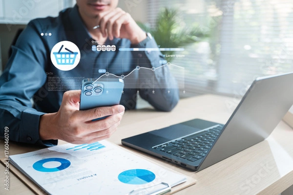 Fototapeta A businessperson managing e-commerce orders on a smartphone and laptop with digital analytics dashboard, representing sales tracking and online transaction management.