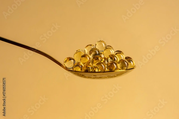 Obraz Capsules of vitamin D3 on a yellow background with free space. Biologically active substances of the calciferol group are fat-soluble organic compounds.