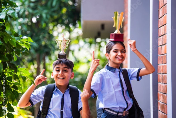 Fototapeta Indian School Kids in Uniform Flaunting Trophy Proudly While Standing Outside and Looking at Camera