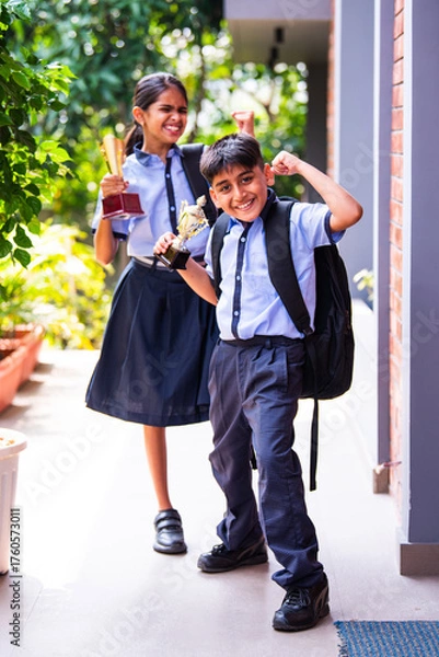 Fototapeta Indian School Kids in Uniform Flaunting Trophy Proudly While Standing Outside and Looking at Camera