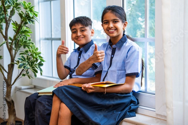 Fototapeta Indian Uniformed students quietly read near classroom window during peaceful self-study time