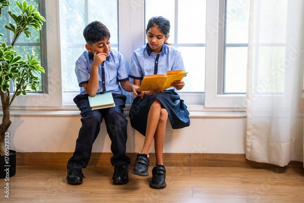 Fototapeta Indian Uniformed students quietly read near classroom window during peaceful self-study time