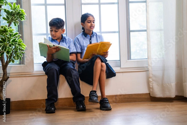 Fototapeta Indian Uniformed students quietly read near classroom window during peaceful self-study time