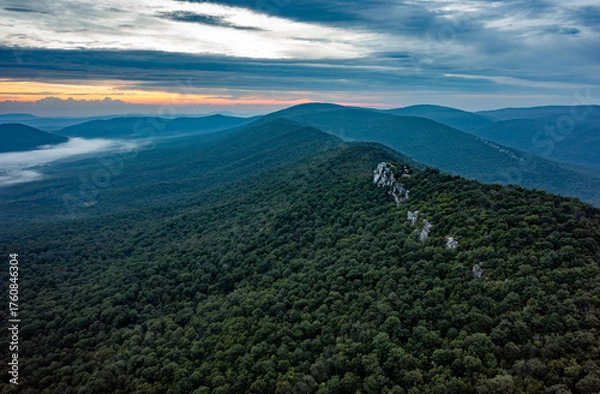 Fototapeta Aerial view of Big Schloss on Great North Mountain at dawn, on the Virginia/West Virginia border. Mist fills the forested valleys as soft sunrise light reveals the rocky ridgeline.