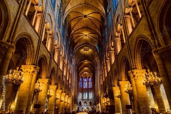 Fototapeta mystical image of the interior of Notre Dame cathedral In Paris with candles of lit faithful illuminated by colored stained glass windows