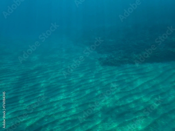 Fototapeta Sunlight shining  the surface and under the blue ocean, sea wave, with clean waters in summer time, Ocean blue underwater with sunrays, underwater blue ocean, sandy sea bottom underwater background.