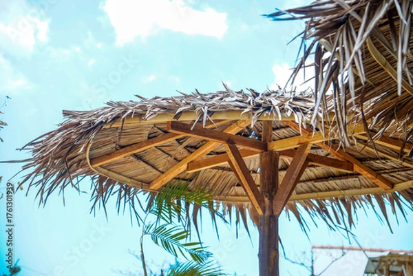 Fototapeta bottom view of a straw umbrella with a wooden frame against a clear sky for advertising space.